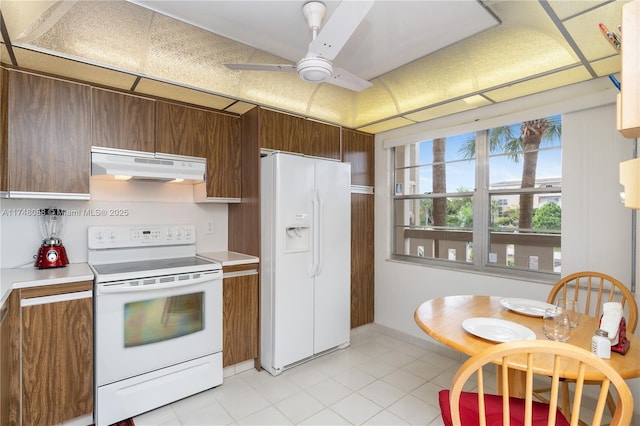 kitchen with white appliances, a ceiling fan, brown cabinets, light countertops, and under cabinet range hood