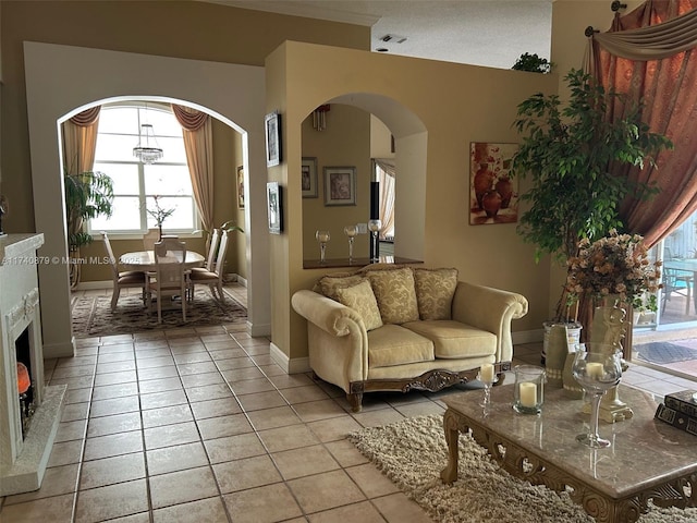 living area with arched walkways, light tile patterned flooring, and baseboards