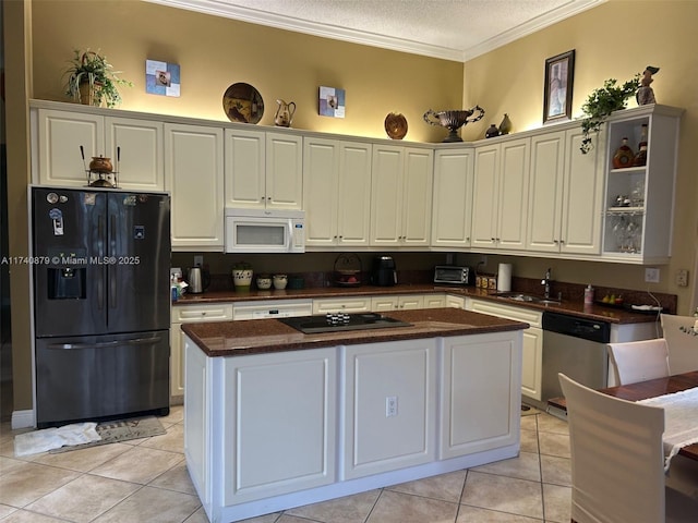 kitchen with white cabinets, dark countertops, a kitchen island, black appliances, and a sink