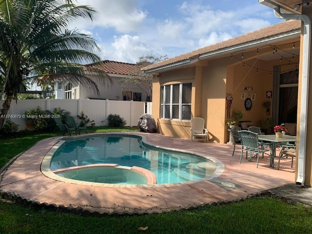 view of swimming pool with a patio area, fence, and a pool with connected hot tub