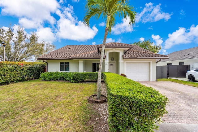 mediterranean / spanish house with decorative driveway, stucco siding, an attached garage, a tiled roof, and a front lawn