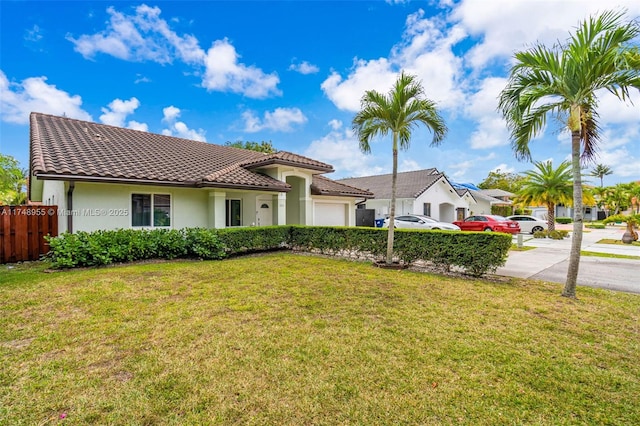 view of front of property with a garage, a tile roof, fence, and a front yard