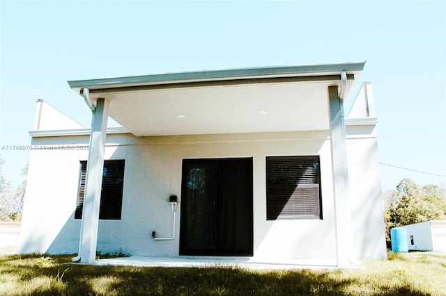 rear view of house featuring stucco siding