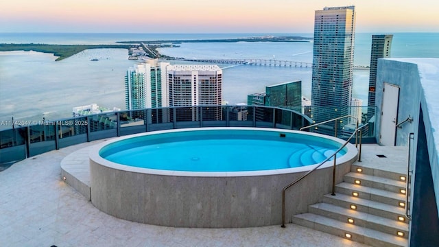 pool at dusk featuring a view of city and a water view