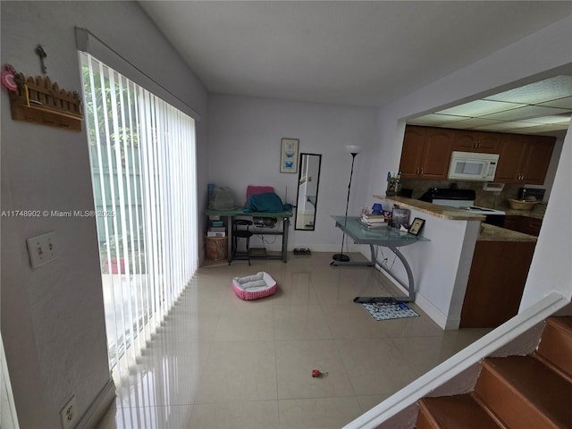 8485 SW 156th Pl Unit 106, Miami, FL 33193 - kitchen featuring white microwave, electric stove, a peninsula, brown cabinets, and light countertops