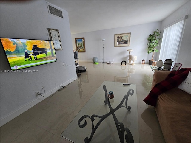 living room featuring baseboards, tile patterned flooring, and visible vents