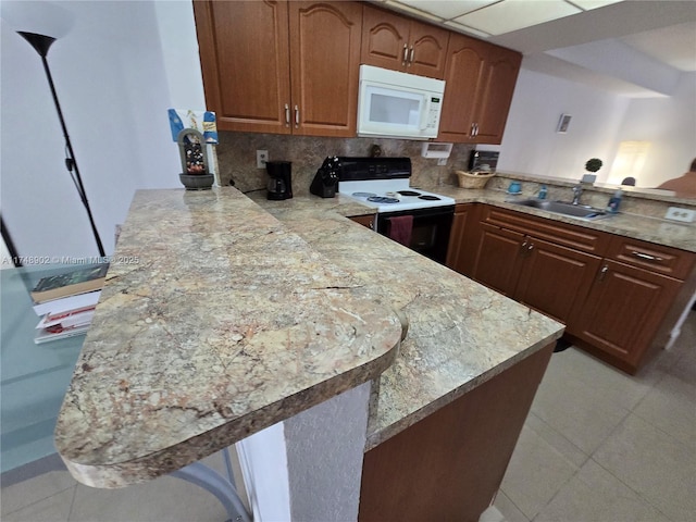 kitchen featuring decorative backsplash, electric range oven, a sink, white microwave, and a peninsula