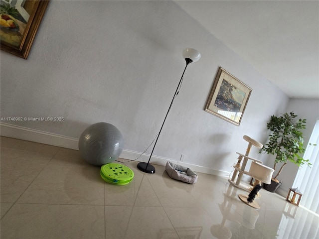exercise room with baseboards and tile patterned floors