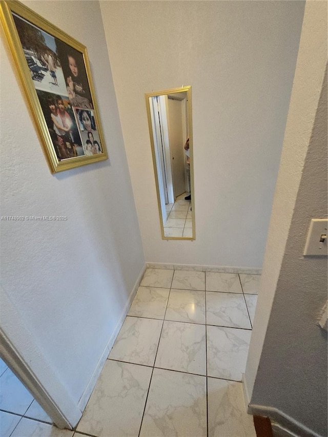 corridor with baseboards and marble finish floor
