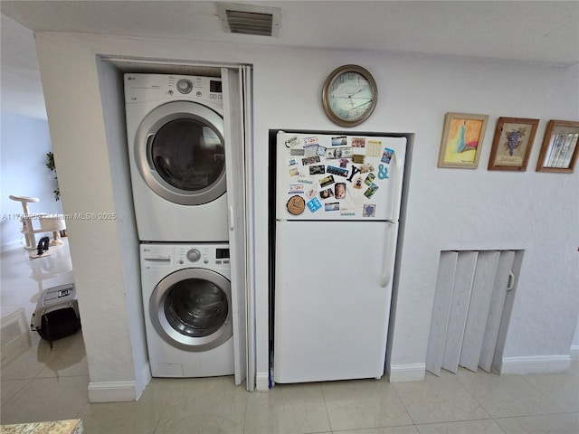 laundry area featuring baseboards, visible vents, stacked washer and clothes dryer, and laundry area