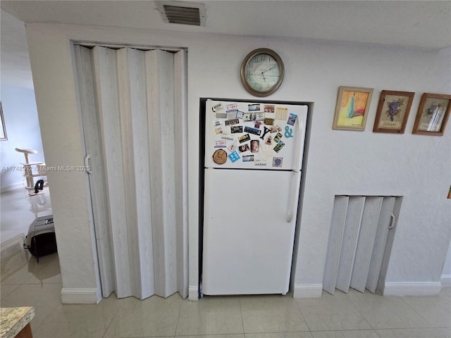 interior space featuring freestanding refrigerator, baseboards, and visible vents