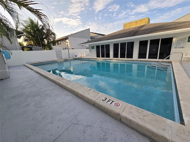 pool with a patio and fence