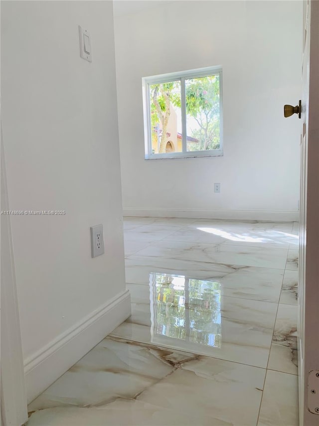 spare room with marble finish floor and baseboards