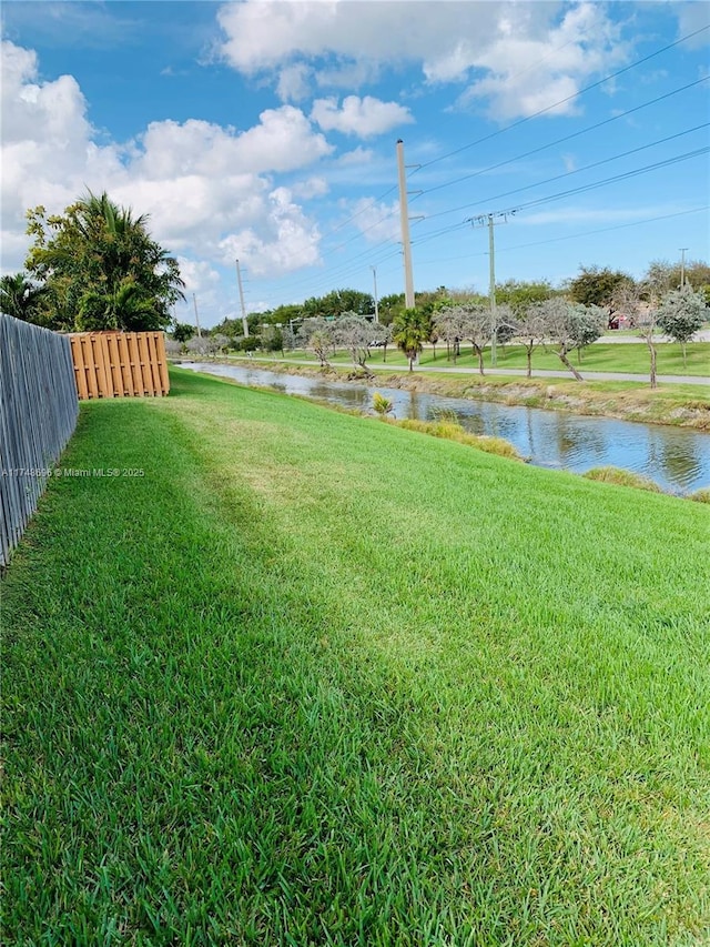 view of yard with a water view and fence