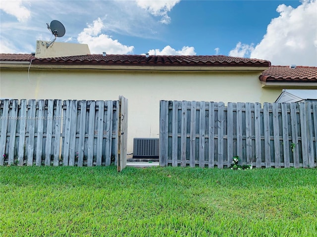 view of home's exterior with central air condition unit, fence, a lawn, and stucco siding