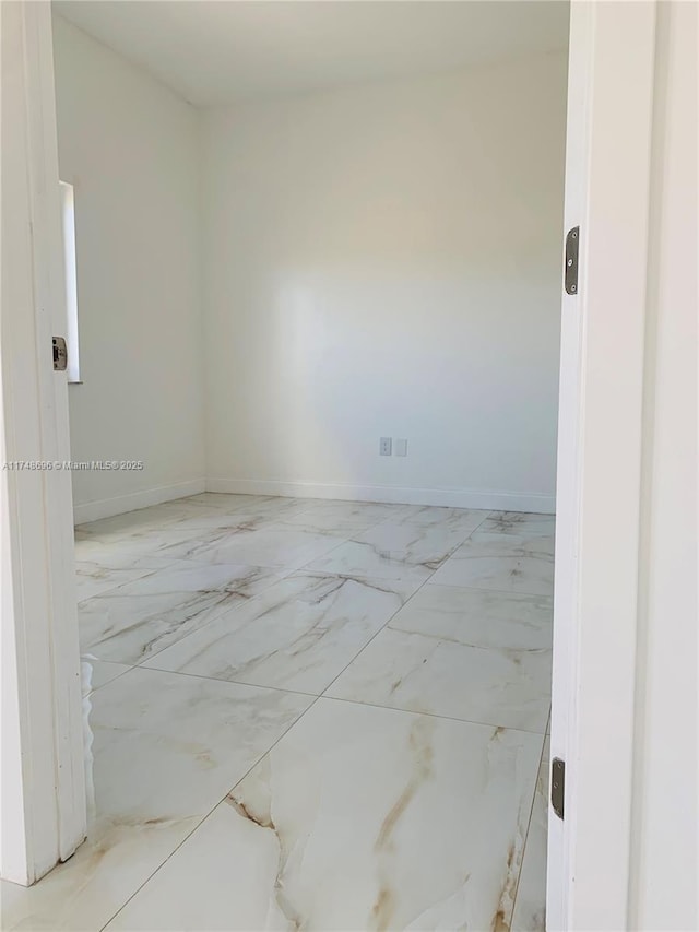 empty room featuring marble finish floor and baseboards