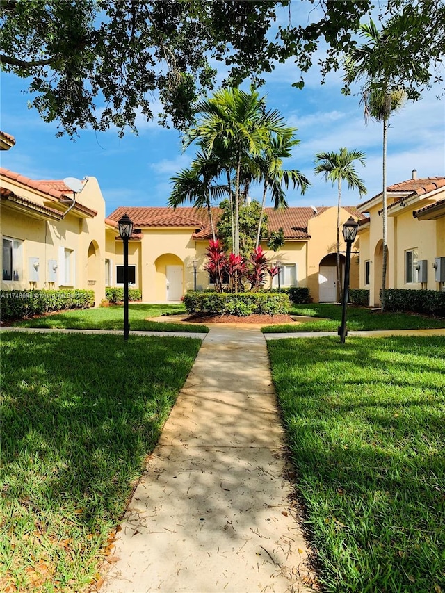 mediterranean / spanish-style house with stucco siding, a tile roof, and a front yard