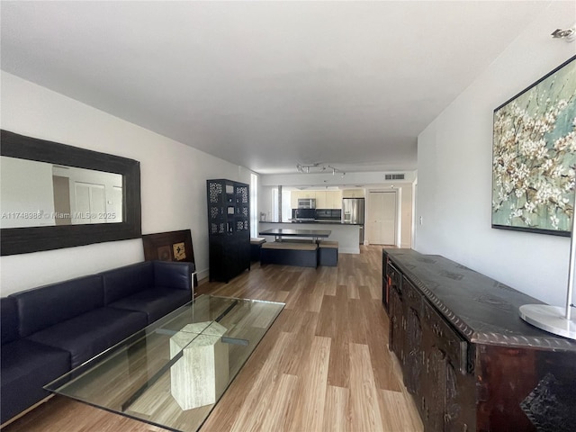 living area with light wood-type flooring, visible vents, and track lighting