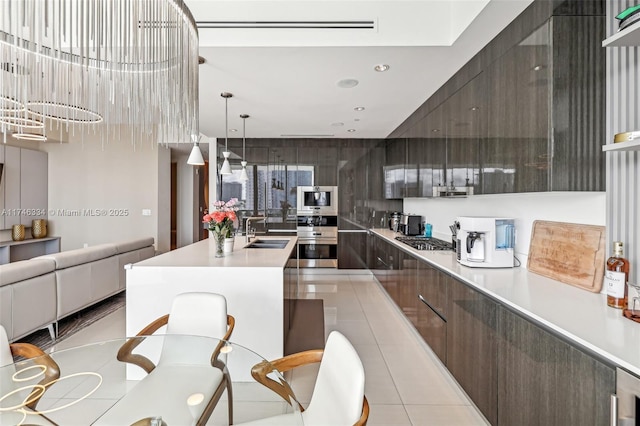 kitchen featuring stainless steel gas cooktop, a center island with sink, light countertops, a sink, and modern cabinets