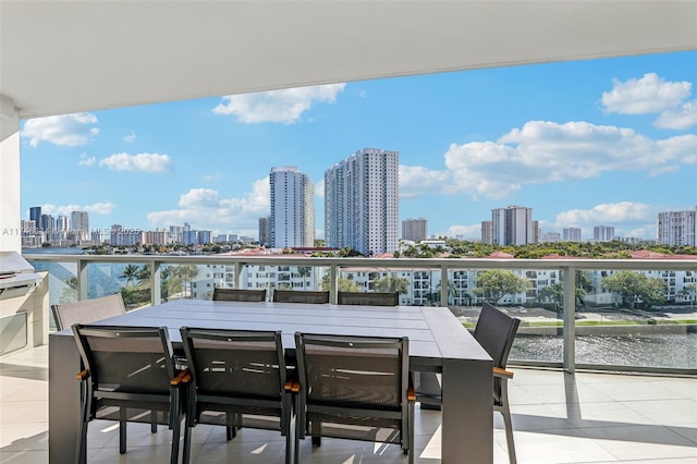 balcony featuring a view of city, outdoor dining area, and a water view