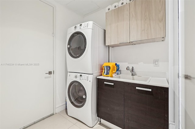 washroom featuring light tile patterned flooring, stacked washing maching and dryer, a sink, and cabinet space