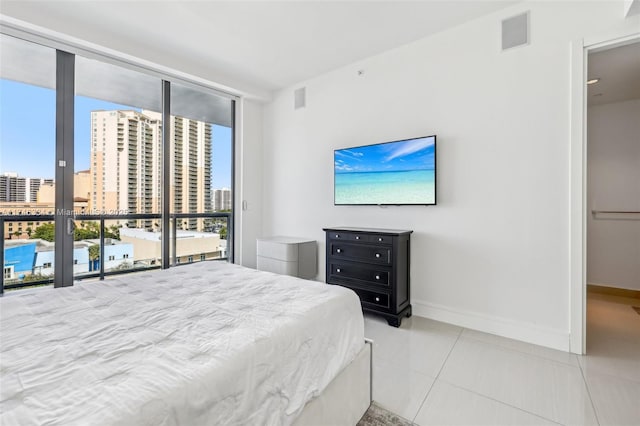 bedroom featuring baseboards, expansive windows, visible vents, and a city view