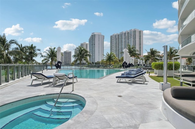community pool featuring a patio area, fence, and a city view