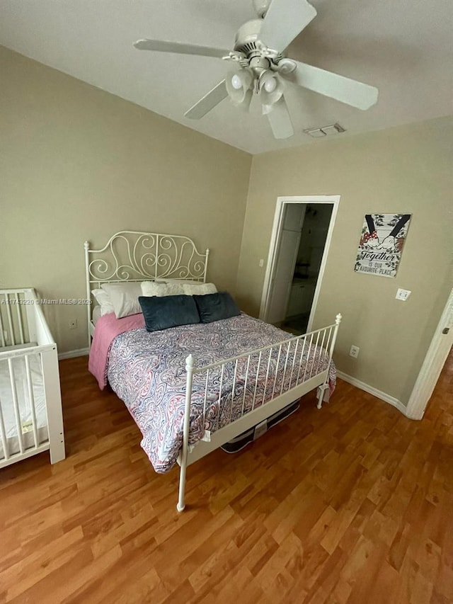 bedroom featuring a ceiling fan, visible vents, baseboards, and wood finished floors