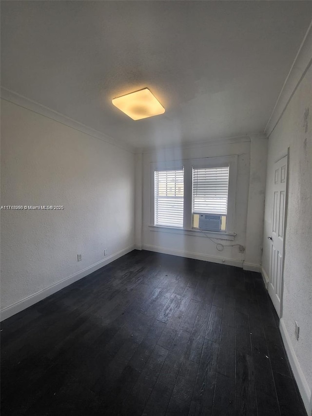 unfurnished room featuring baseboards, a textured wall, dark wood-style flooring, and crown molding