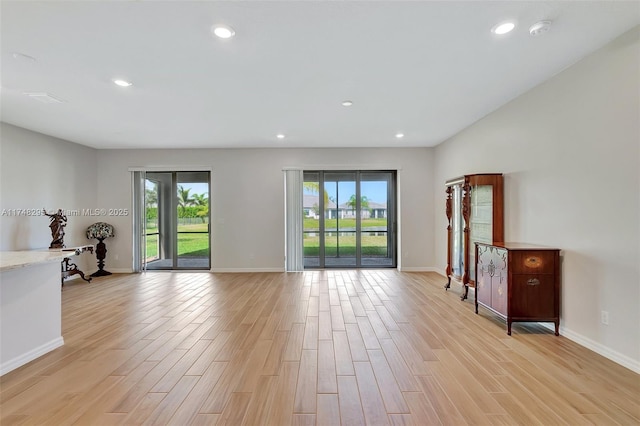 unfurnished living room featuring light wood-type flooring, baseboards, a wealth of natural light, and recessed lighting