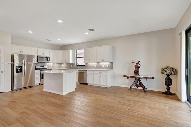 kitchen with visible vents, white cabinets, appliances with stainless steel finishes, backsplash, and light wood finished floors