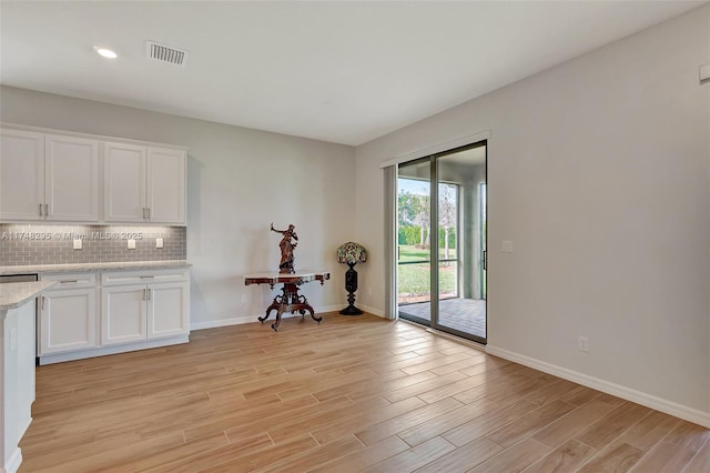 kitchen with visible vents, decorative backsplash, baseboards, light wood-style flooring, and white cabinetry