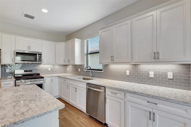 kitchen with light wood finished floors, visible vents, appliances with stainless steel finishes, white cabinets, and a sink