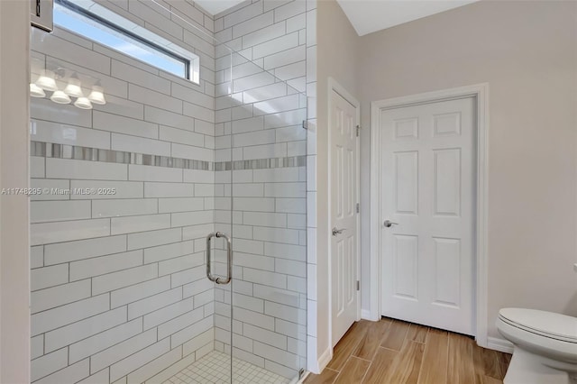 bathroom featuring baseboards, a shower stall, toilet, and wood finished floors