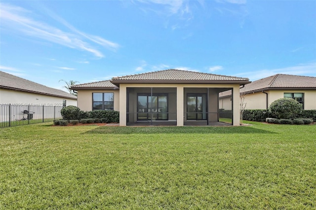 back of house featuring a sunroom, a tile roof, a lawn, and fence