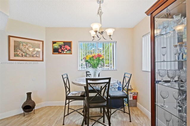 801 Sw 141 101O, Pembroke Pines, FL 33027 - dining room featuring light wood-style floors, baseboards, and a notable chandelier