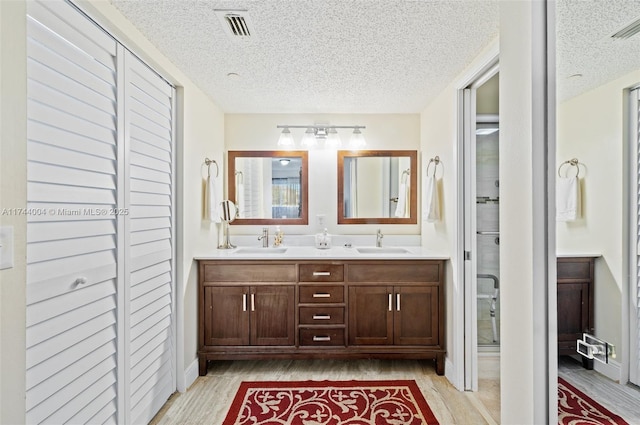 801 Sw 141 101O, Pembroke Pines, FL 33027 - full bath with double vanity, a textured ceiling, a sink, and wood finished floors