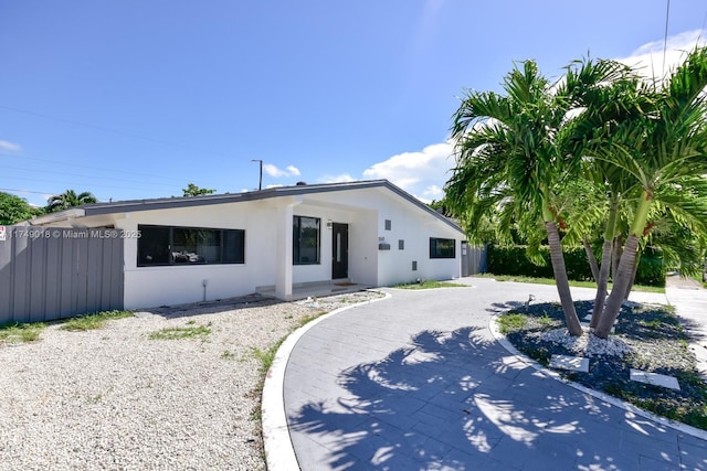 view of front of house featuring driveway, fence, and stucco siding