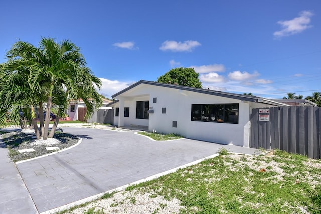 view of front facade with driveway, fence, and stucco siding