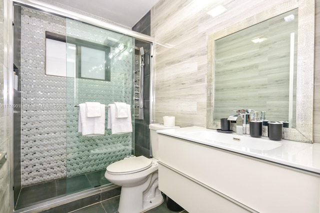 full bath featuring toilet, tile patterned flooring, a tile shower, vanity, and tile walls