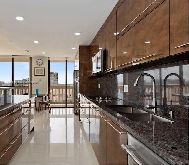 kitchen featuring stainless steel microwave, a wall of windows, decorative backsplash, black electric cooktop, and a sink