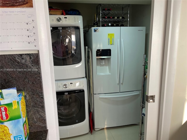 laundry room featuring tile patterned floors, stacked washer and clothes dryer, and laundry area