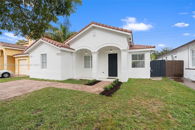 mediterranean / spanish-style house featuring a garage, fence, a front lawn, and stucco siding