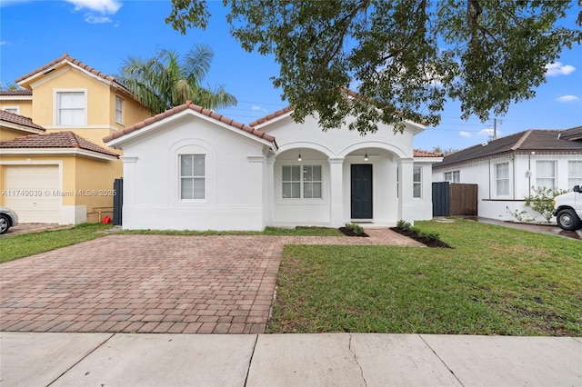 mediterranean / spanish-style home with a tile roof, a front lawn, and stucco siding