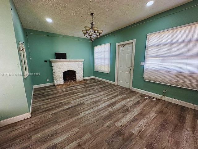 unfurnished living room with dark wood-style floors, a fireplace, baseboards, and a notable chandelier