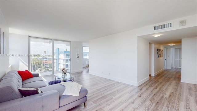 living room with baseboards, expansive windows, visible vents, and light wood-style floors