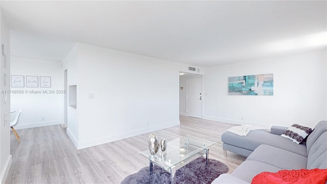 living room with visible vents, light wood-style flooring, and baseboards