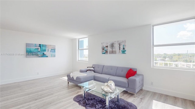 living area with light wood-style floors, plenty of natural light, and baseboards