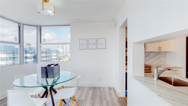 dining area featuring baseboards, light wood-style flooring, visible vents, and a city view