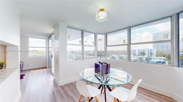 dining area featuring a view of city, baseboards, and light wood finished floors